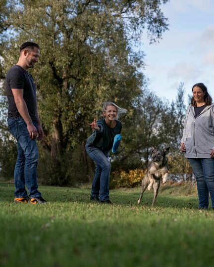 Vier Akademie-Dozierende, die mit einem Hund in der Natur stehen