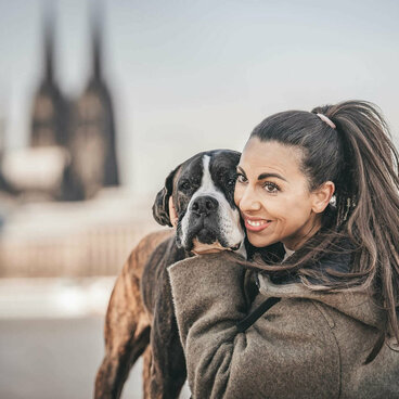 Frau umarmt Hund am Rhein