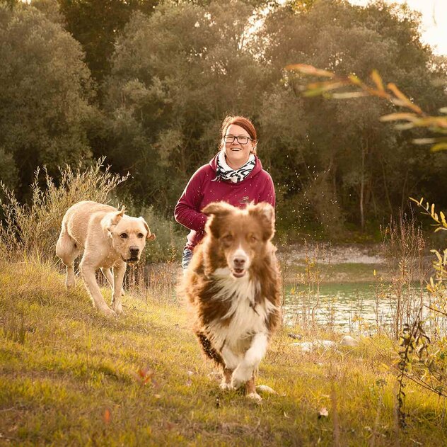Steffi mit zwei rennenden Hunden auf der Wiese 